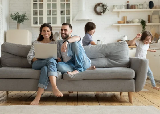 couple sitting in sofa while kids are running around